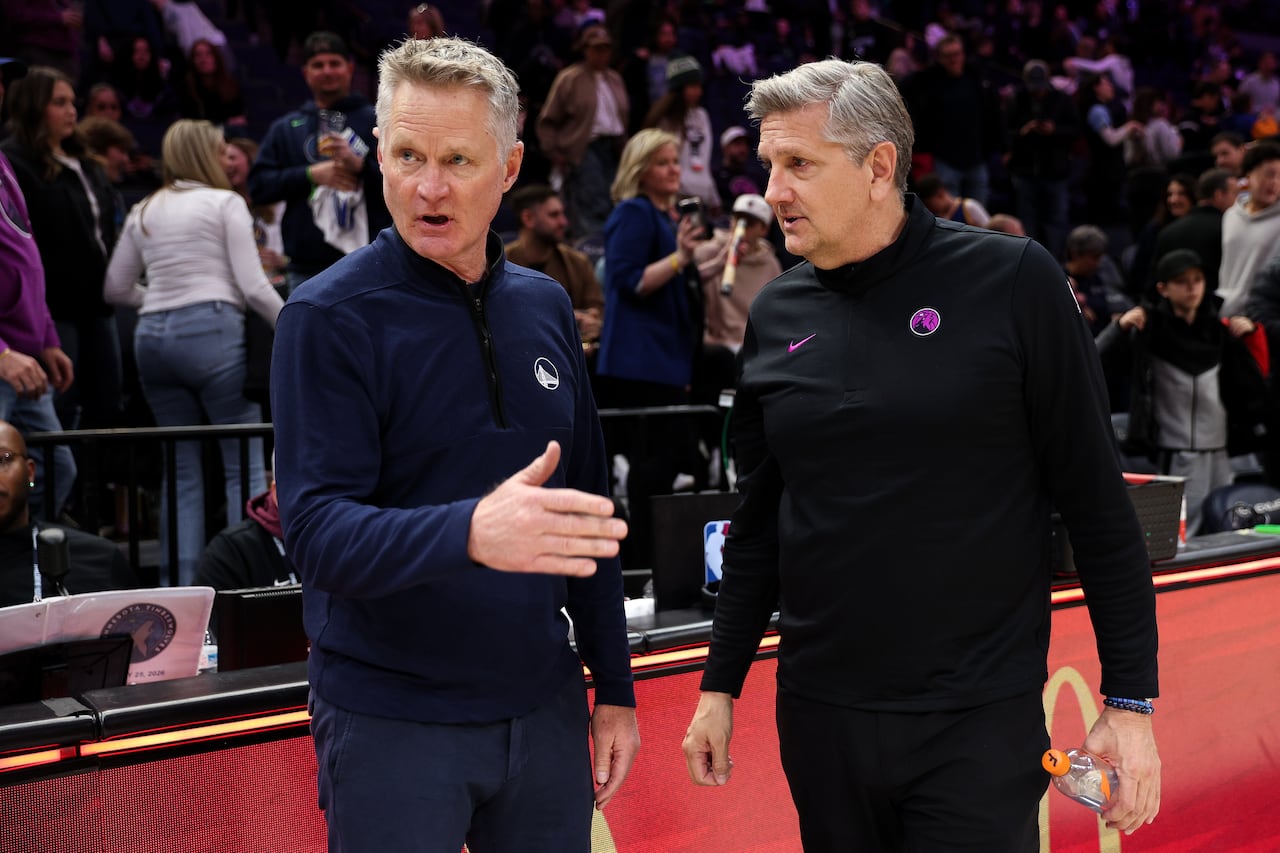 Two basketball coaches converse on the court.