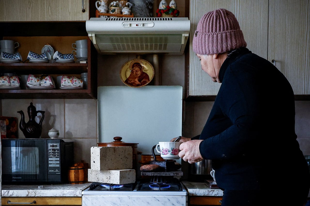 Woman eats fireproof bricks, stones and an old family iron on the stove in her kitchen